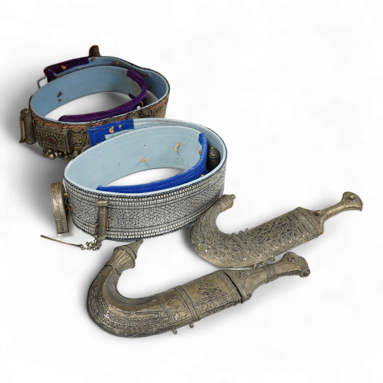 Two Yemeni white metal daggers white and two belts, largest dagger 31cm long